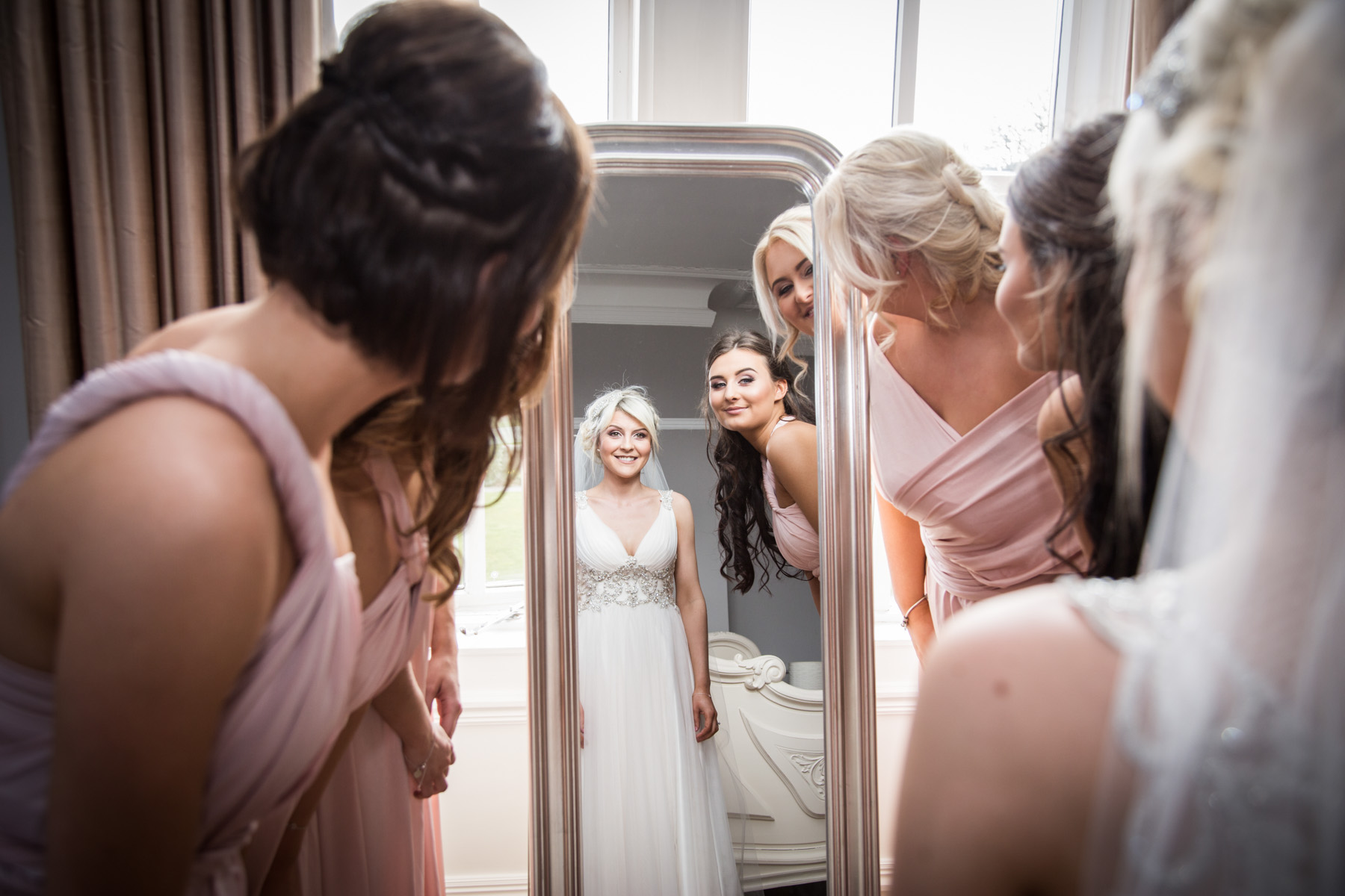bridesmaids looking at bride in mirror